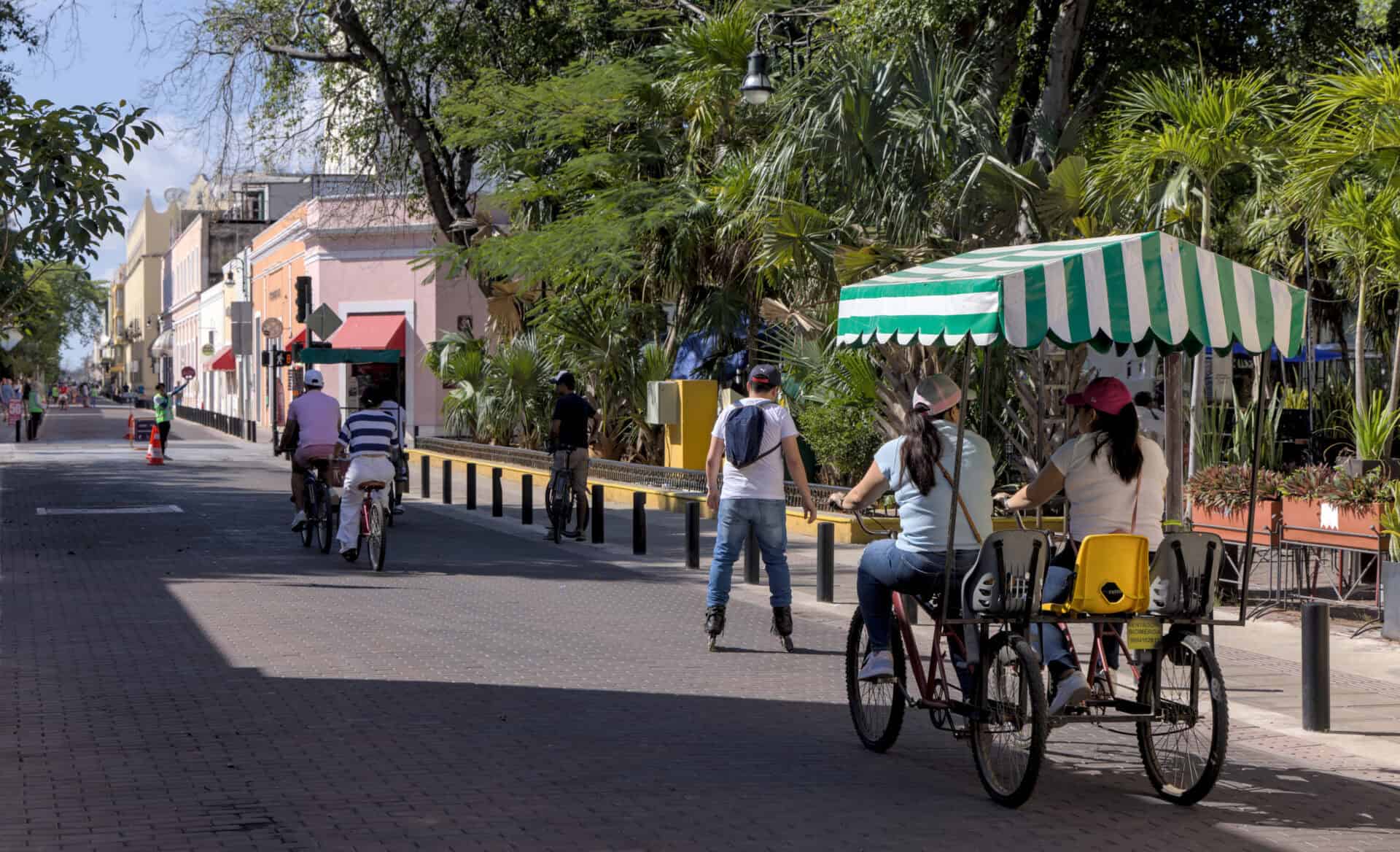 People riding bicycles on colorful colonial streets of merida yucatan mexico during sunday weekly biciruta event when streets are closed to traffic downtown.