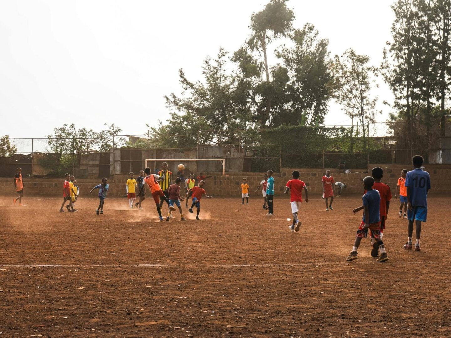 Energetic youth soccer match on a dusty field in Addis Ababa, Ethiopia with vibrant uniforms.