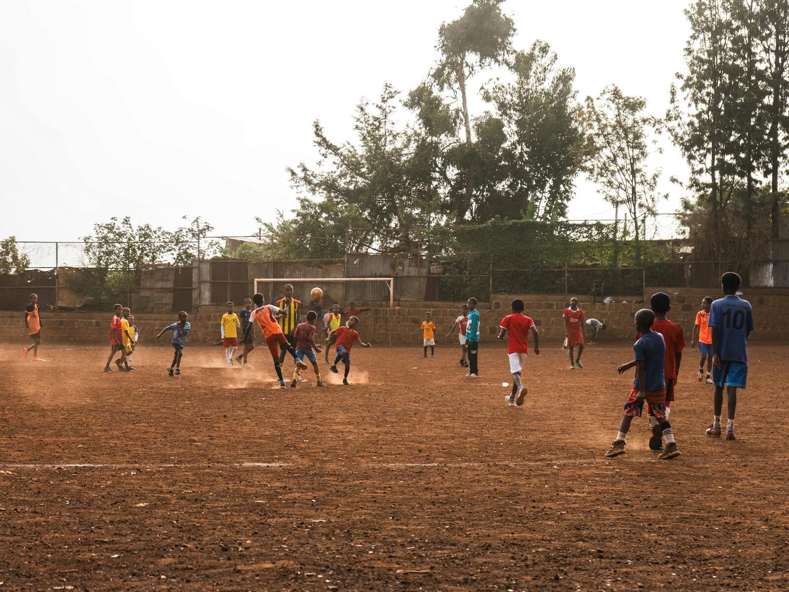 Energetic youth soccer match on a dusty field in Addis Ababa, Ethiopia with vibrant uniforms.